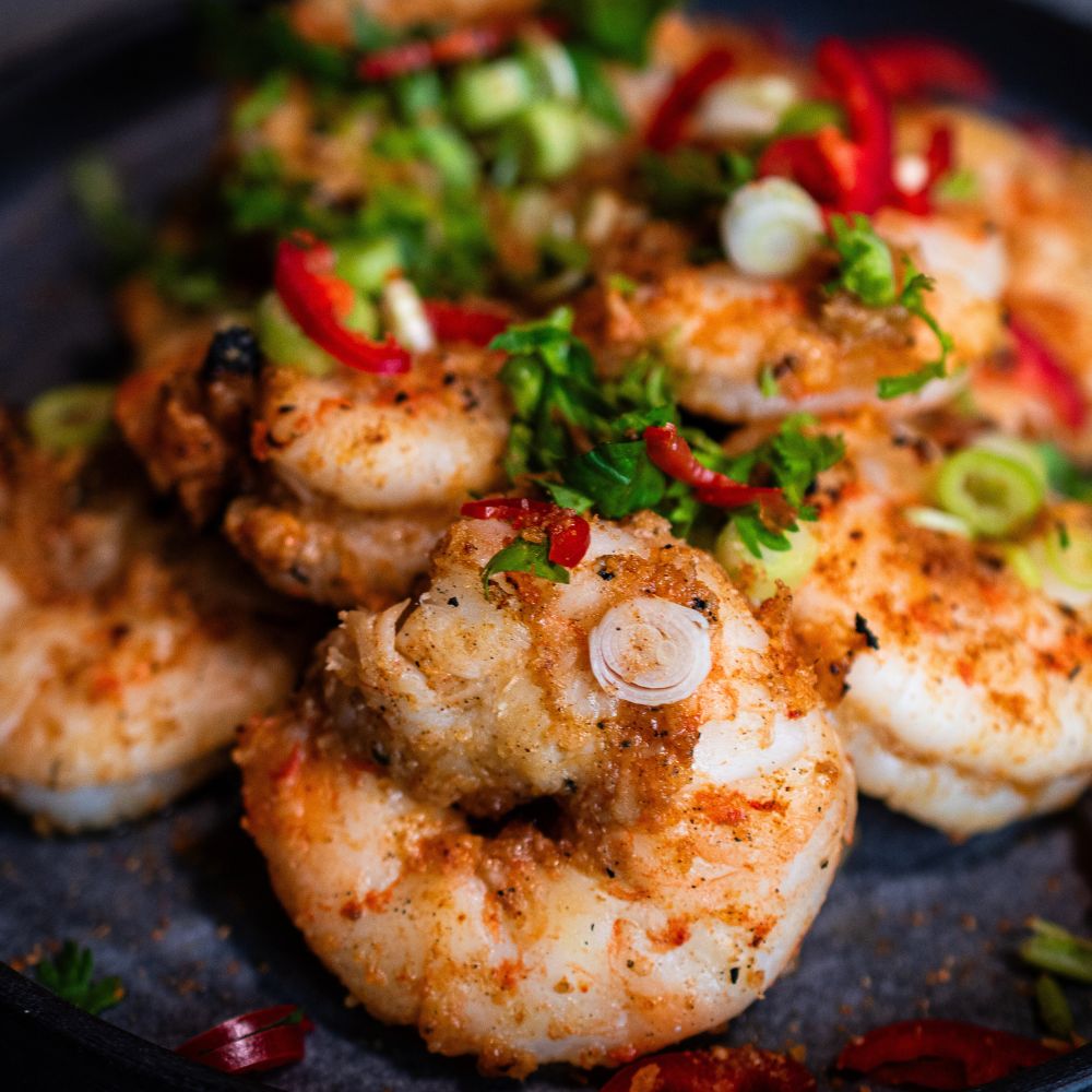 Ananas Teriyaki Gewürz Eine Nahaufnahme einer Portion marinierter Garnelen mit Ananas Teriyaki Marinade und geschnittenen Lauchzwiebeln und Thai Basilikum getoppt.