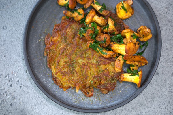 Mit Chimichurri gewürzte Kartoffelrösti und Pilze serviert auf flachem Teller