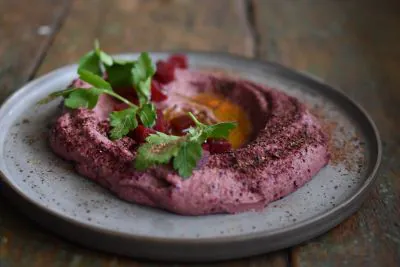 Ein Hummus-Gericht auf einem Teller, schräg von vorn fotografiert.