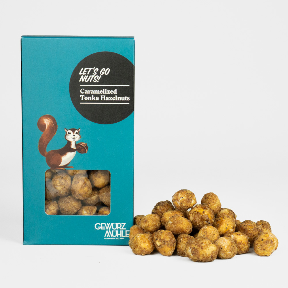 Nüsse in Pappverpackung mit Sichtfenster, ausgeschüttete Nüsse daneben - Caramelized Tonka Hazelnuts