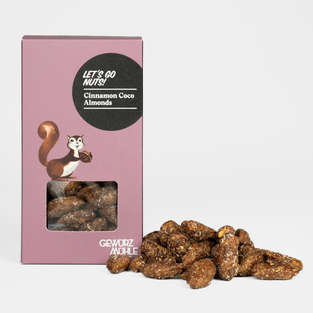 Nüsse in Pappverpackung mit Sichtfenster, ausgeschüttete Nüsse daneben - Cinnamon Coco Almonds