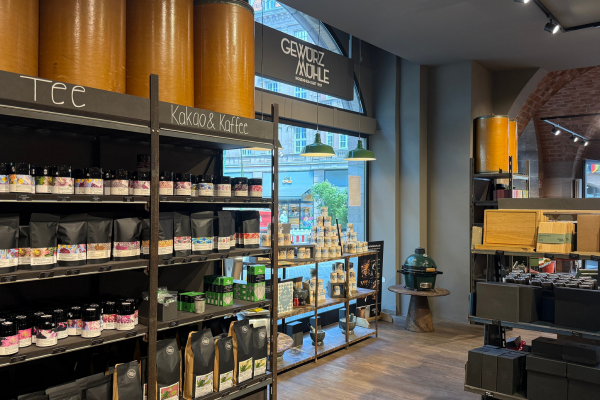 Innenansicht des Gewürzladens der Gewürzmühle Rosenheim in Nürnberg mit Tee, Kaffee und Kakao im Regal, Geschenkartikeln, Gewürzprodukten und einem Big Green Egg als Teil der hochwertigen Ladenpräsentation.