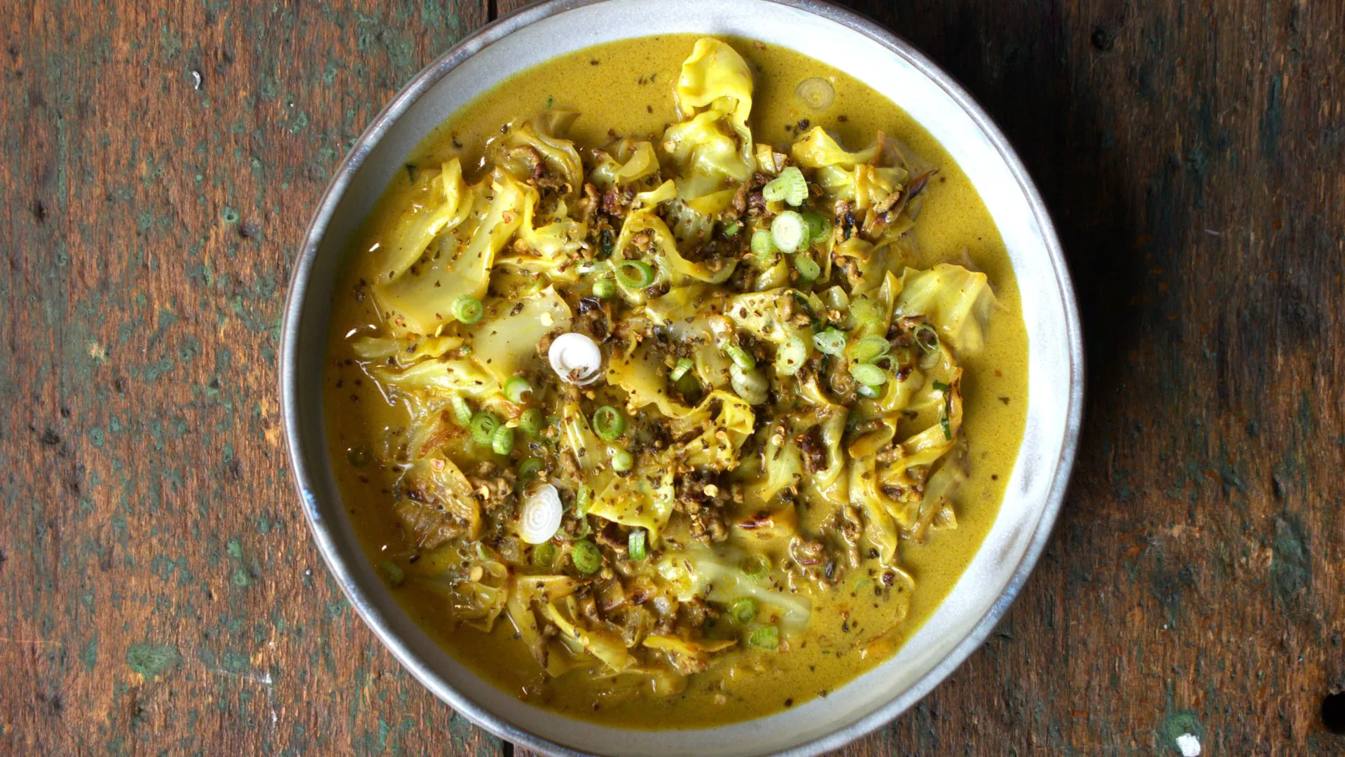 Curry-Gericht in weißer Schale serviert auf Holzuntergrund