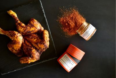 Knuspriges Hähnchen und umgefallene Cajun-Spice Gewürzdosen auf dunklem Untergrund