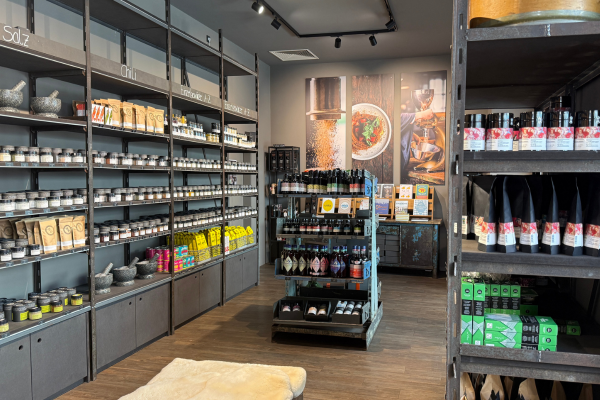 Blick durch den Gewürzladen der Gewürzmühle Rosenheim in Nürnberg mit Regalen voller Gewürze, Salze, Chilis, Tee, Feinkostprodukten sowie einer zentralen Präsentationsfläche mit Ölen, Saucen und weiteren kulinarischen Spezialitäten.