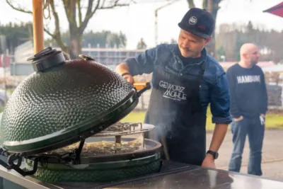 Küchenmeister Swen Philipp steht am Big Green Egg und wirft einen Blick auf das Grillgut