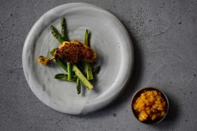 Baharathuhn mit Spargel auf einem Teller und einer Schale mit Chutney daneben