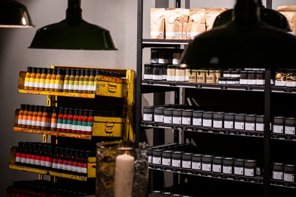 Zwei gut gefüllte Regale im Gewürzladen in Regensburg. Ein Regal gefüllt mit verschiedenen Saucen, eines mit Gewürzdosen und Feinkostartikeln.