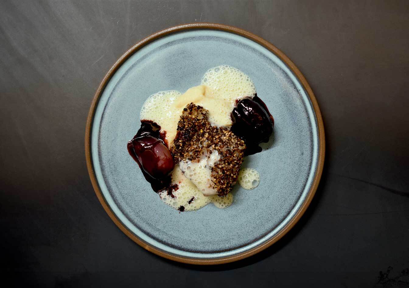 Melange Noir, Pfeffermischung, geschrotet Rotbarschfilet mit knuspriger Gewürzkruste, cremigem Schaum und geschmorter roter Bete auf einem hellblauen Keramikteller – fein angerichtetes Fischgericht mit intensiven Aromen, ideal für moderne Genussküche.