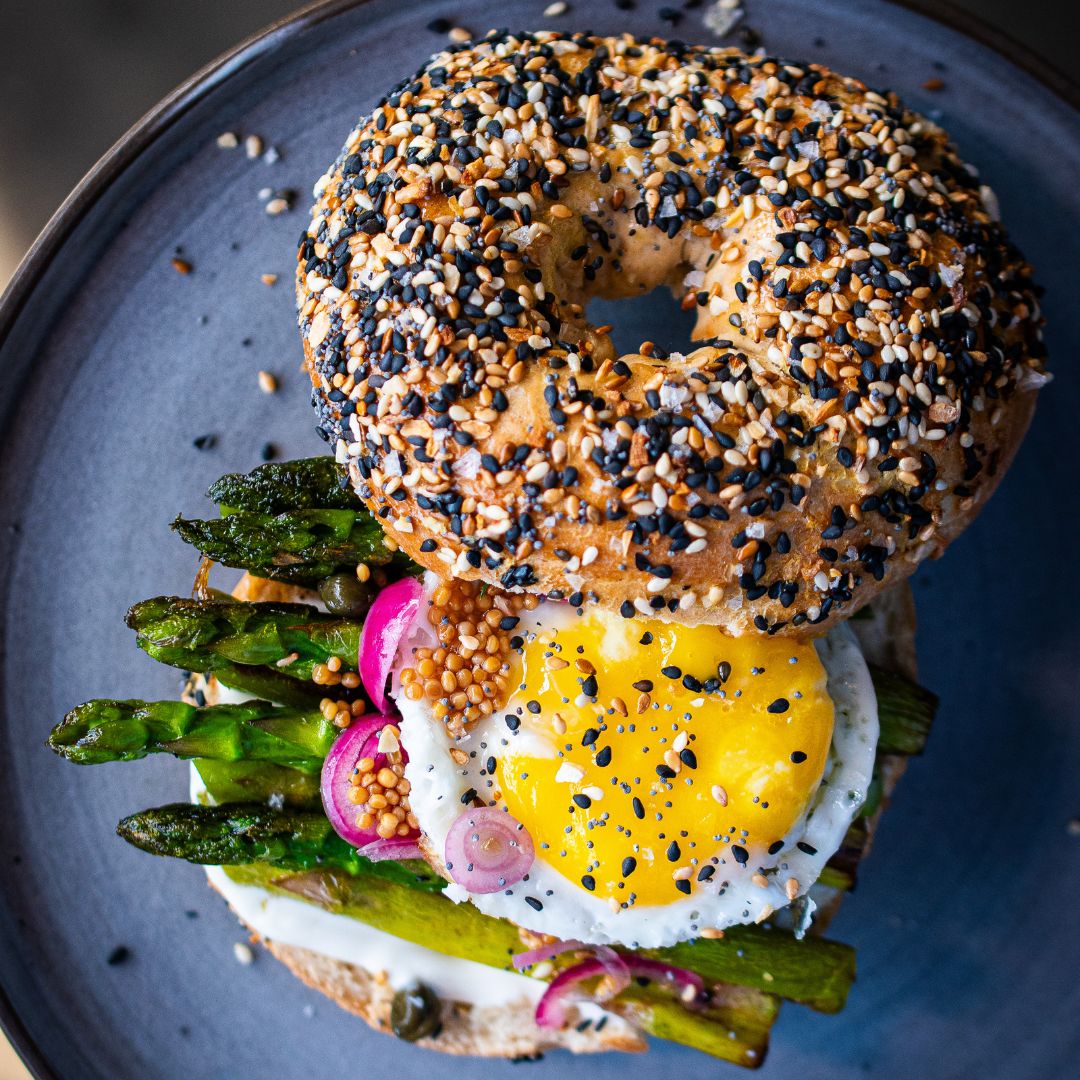 Bagel Sandwich mit grünem Spargel, Spiegelei, Kapern und Topping aus Everything Bagel Gewürz