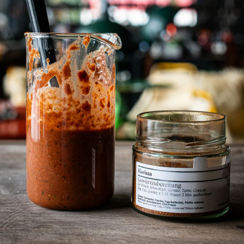 Glas mit würziger Harissa Paste und Löffel daneben, zubereitet mit Harissa Gewürz der Gewürzmühle Rosenheim