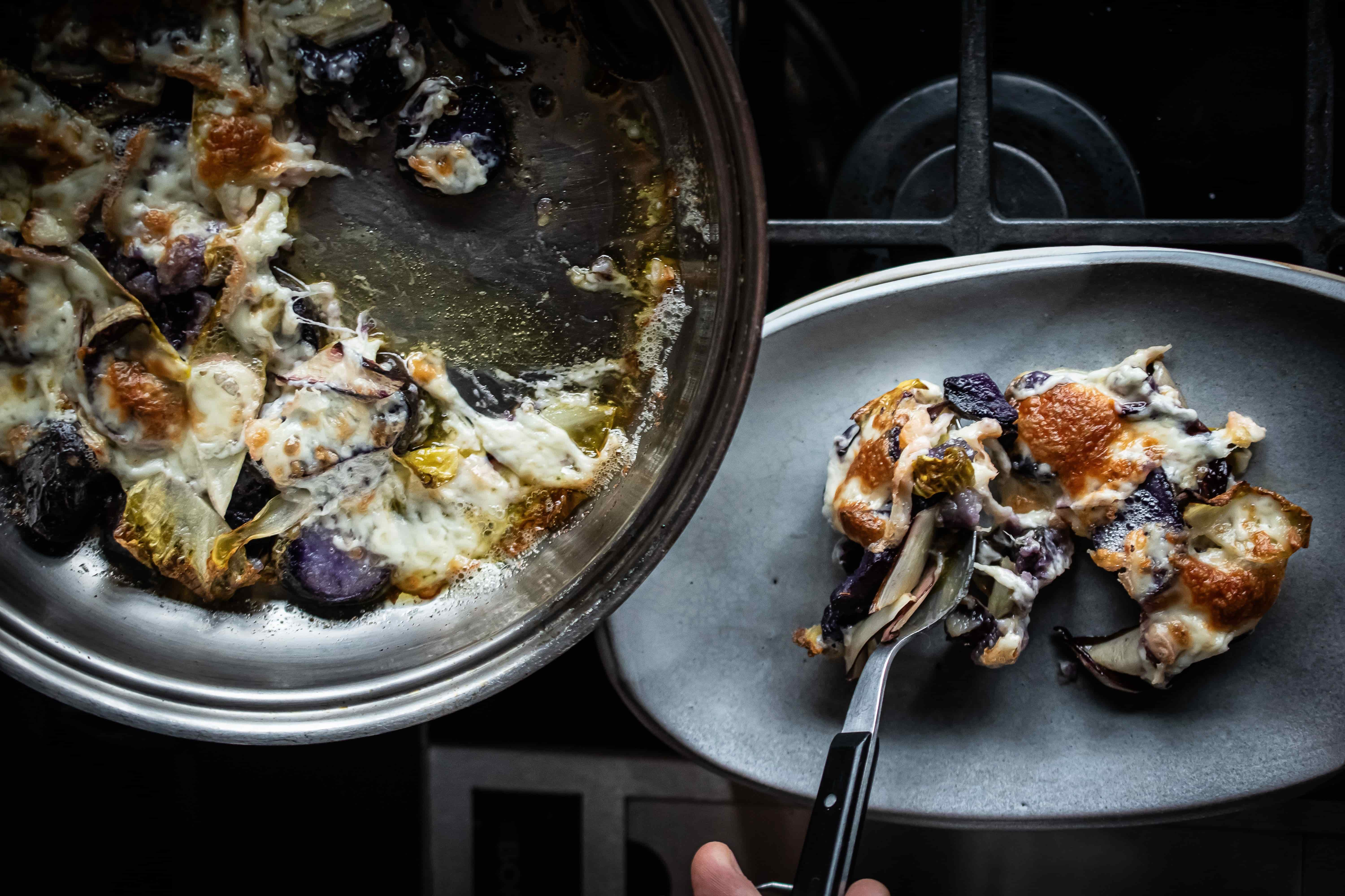 Violette Kartoffelscheiben mit geschmolzenem Taleggio aus der Pfanne auf Teller angerichtet von Gewürzmühle Rosenheim