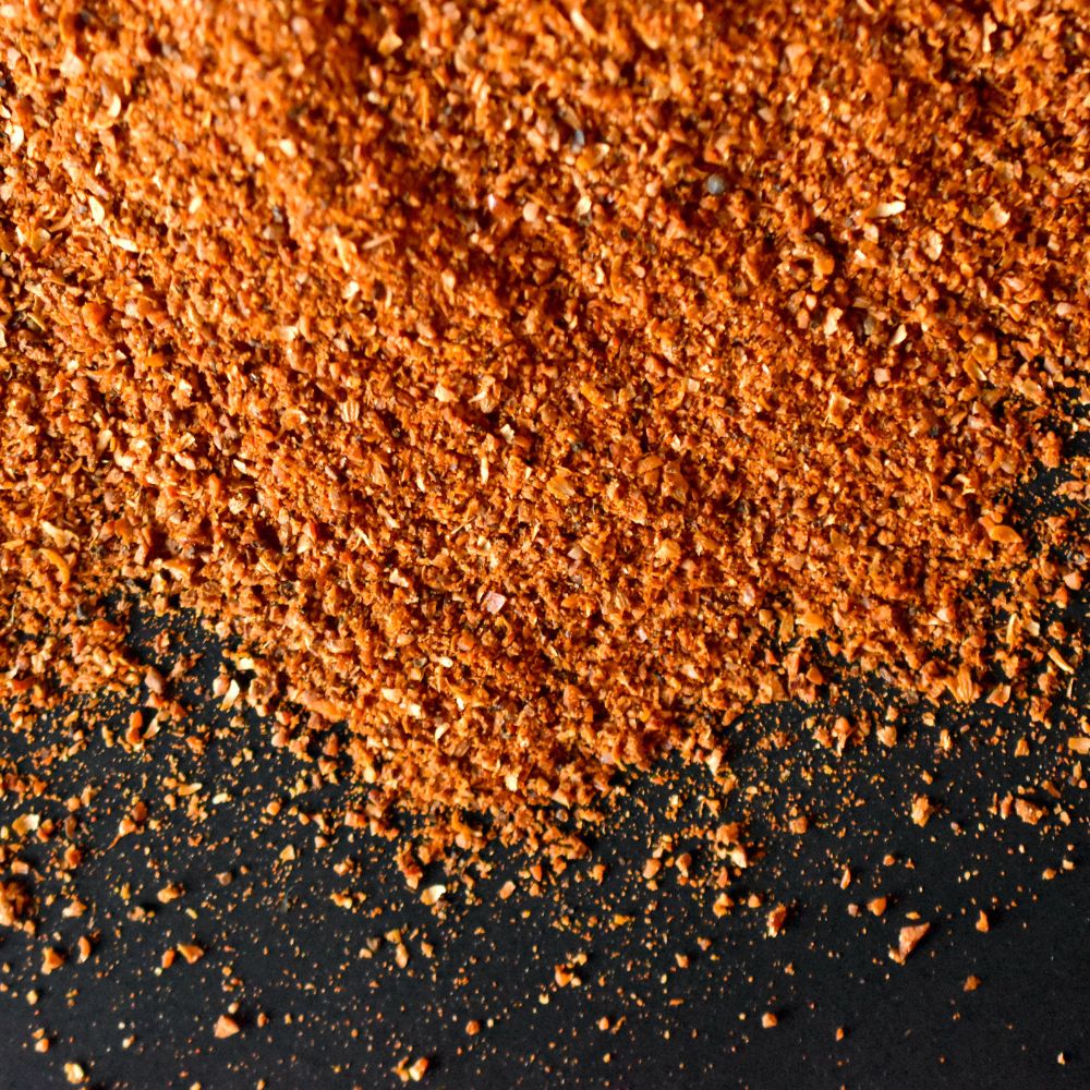 Harissa Harissa Gewürz auf schwarzem Untergrund verstreut