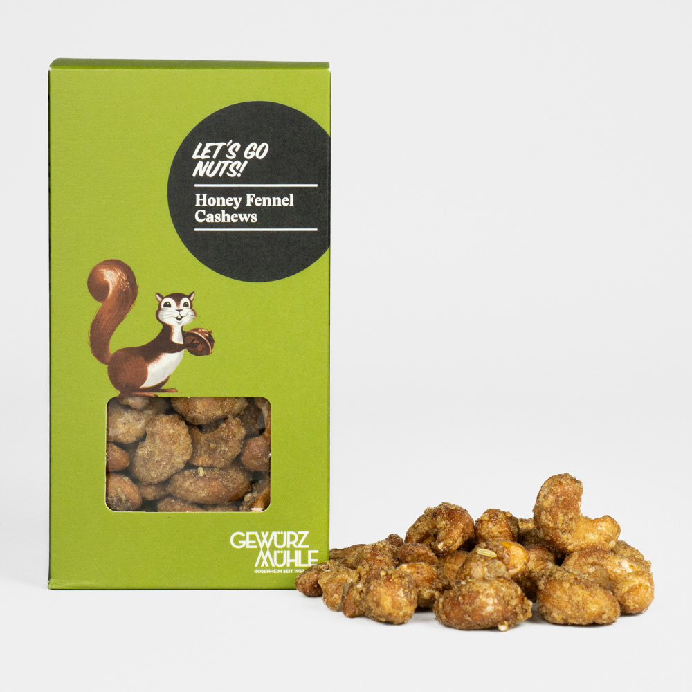 Nüsse in Pappverpackung mit Sichtfenster, ausgeschüttete Nüsse daneben - Honey Fennel Cashews