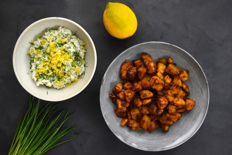 Knusprige mit Cajun Spice gewürzte Kartoffeln und Kräuterquark mit einer Zitrone und Schnittlauch serviert