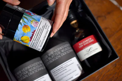 Mehrere Gewürzdosen in einer Geschenkbox. Eine Gewürzdose in der Hand einer Person.