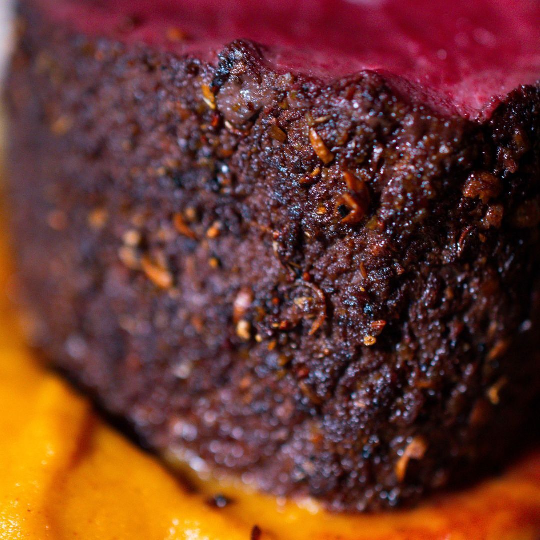 Nahaufnahme eines Stücks Rehrücken, das auf Süßkartoffelcreme platziert ist - die Struktur der Kruste mit der Five Spice Gewürzmischung ist im Fokus.