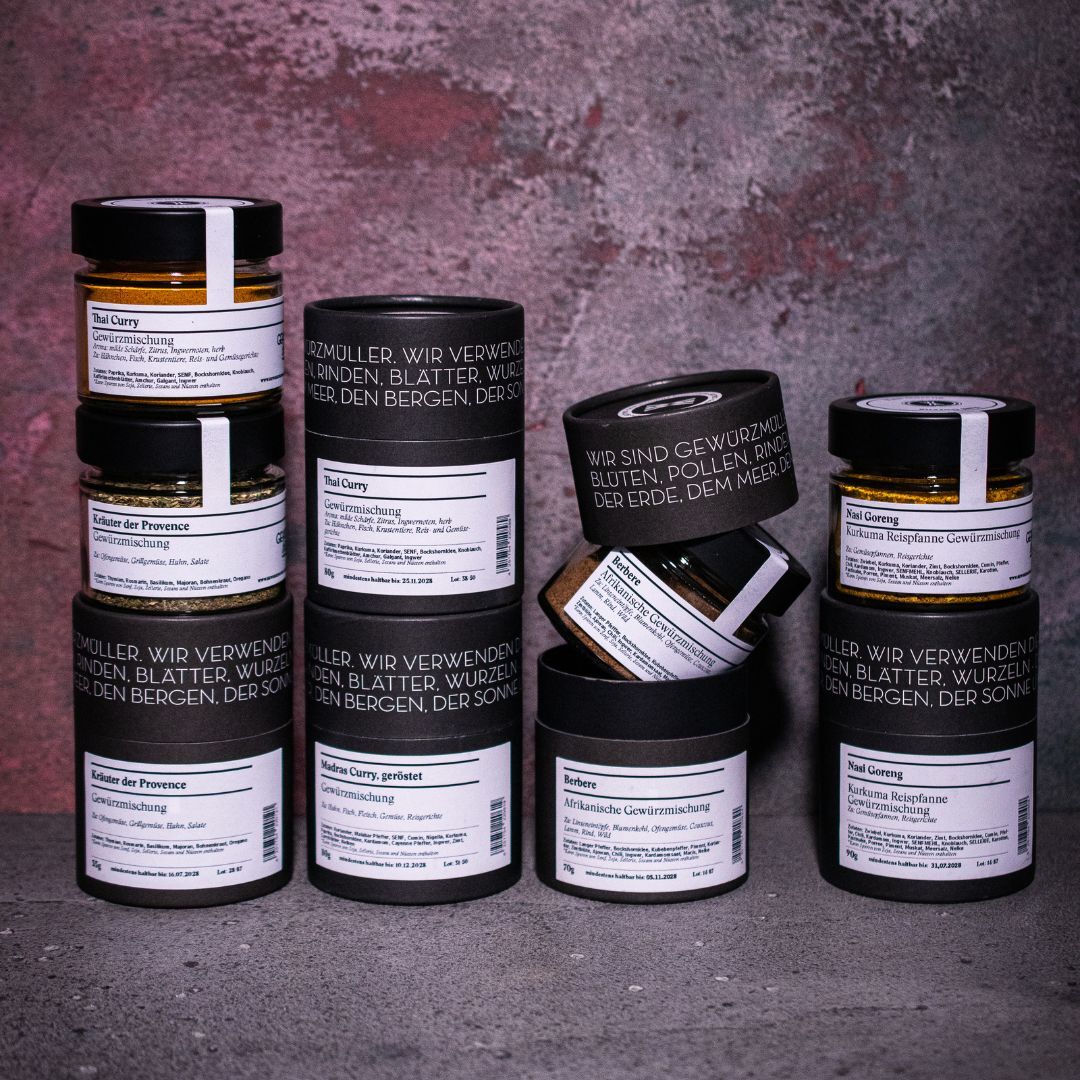 Das Gemüse Set aus der Gewürzmühle Rosenheim mit fünf Gewürzdosen stehend vor einem marmorierten Hintergrund. Das Set enthält die Gewürze: Thai Curry, Kräuter der Provence, Madras Curry, Berbere und Nasi Goreng.