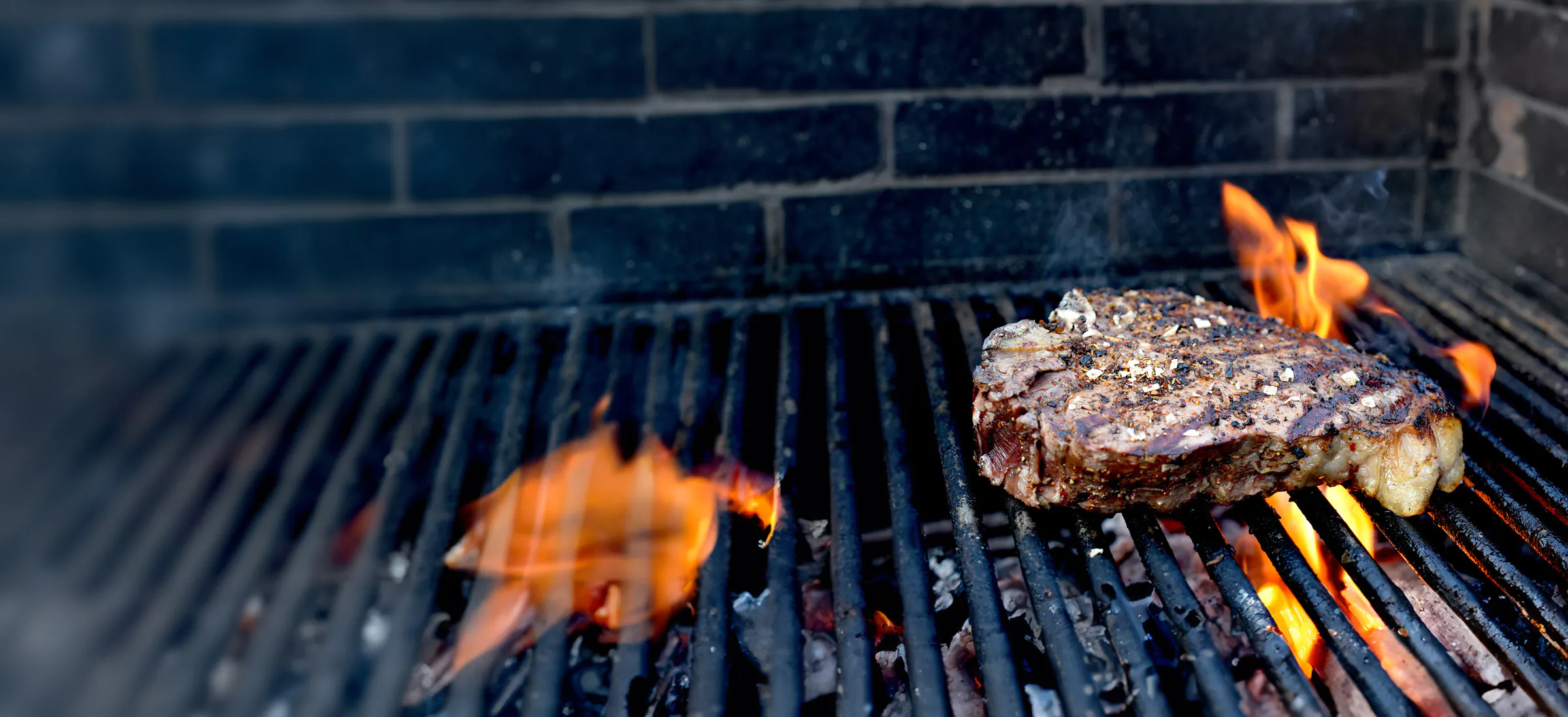 dsc_0195-26xx Saftiges Steak auf einem Grill liegend und von Flammen umgeben