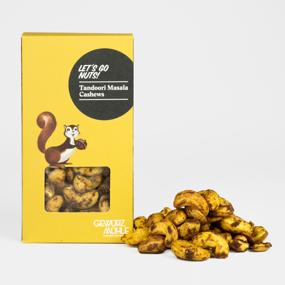 Nüsse in Pappverpackung mit Sichtfenster, ausgeschüttete Nüsse daneben - Tandoori Masala Cashews