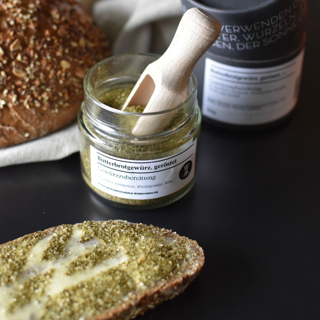 Butterbrotgewürz, geröstet Butterbrotgewürz, geröstet - Gewürzmischung im Glas mit kleiner Holzschaufel und Butterbrot im Vordergrund