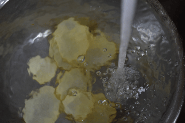 Kartoffelscheiben in hohem Topf, der mit Wasser befüllt wird