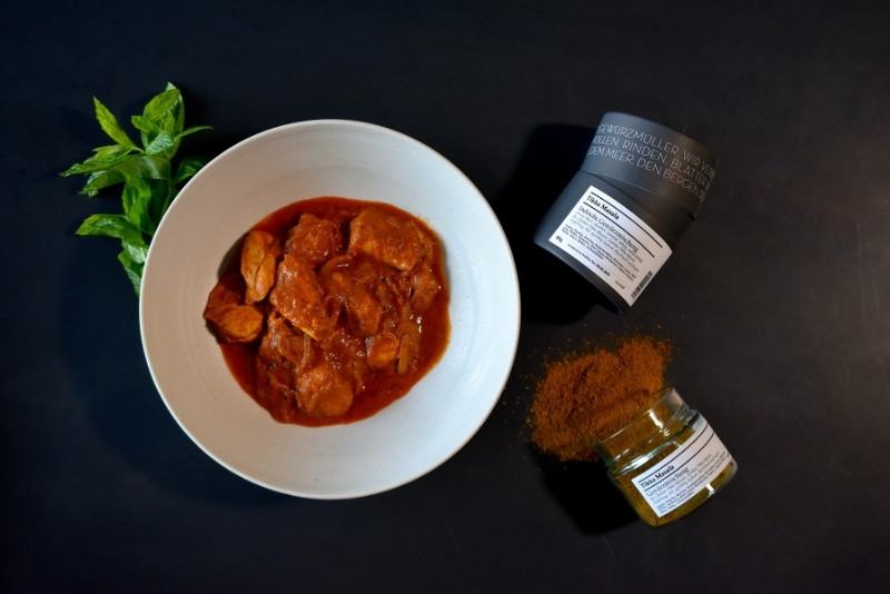 Indisches Gericht und zwei indische Gewürze auf schwarzem Untergrund