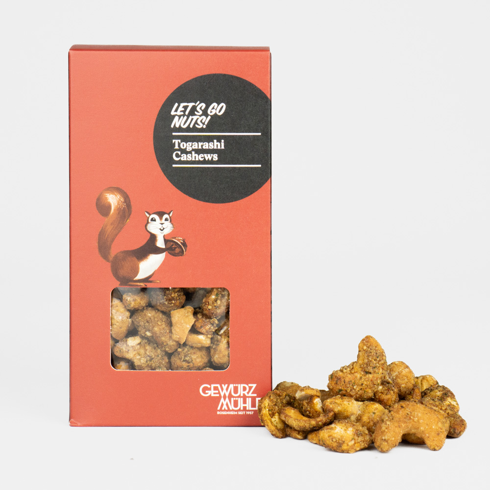 Nüsse in Pappverpackung mit Sichtfenster, ausgeschüttete Nüsse daneben - Togarashi Cashews
