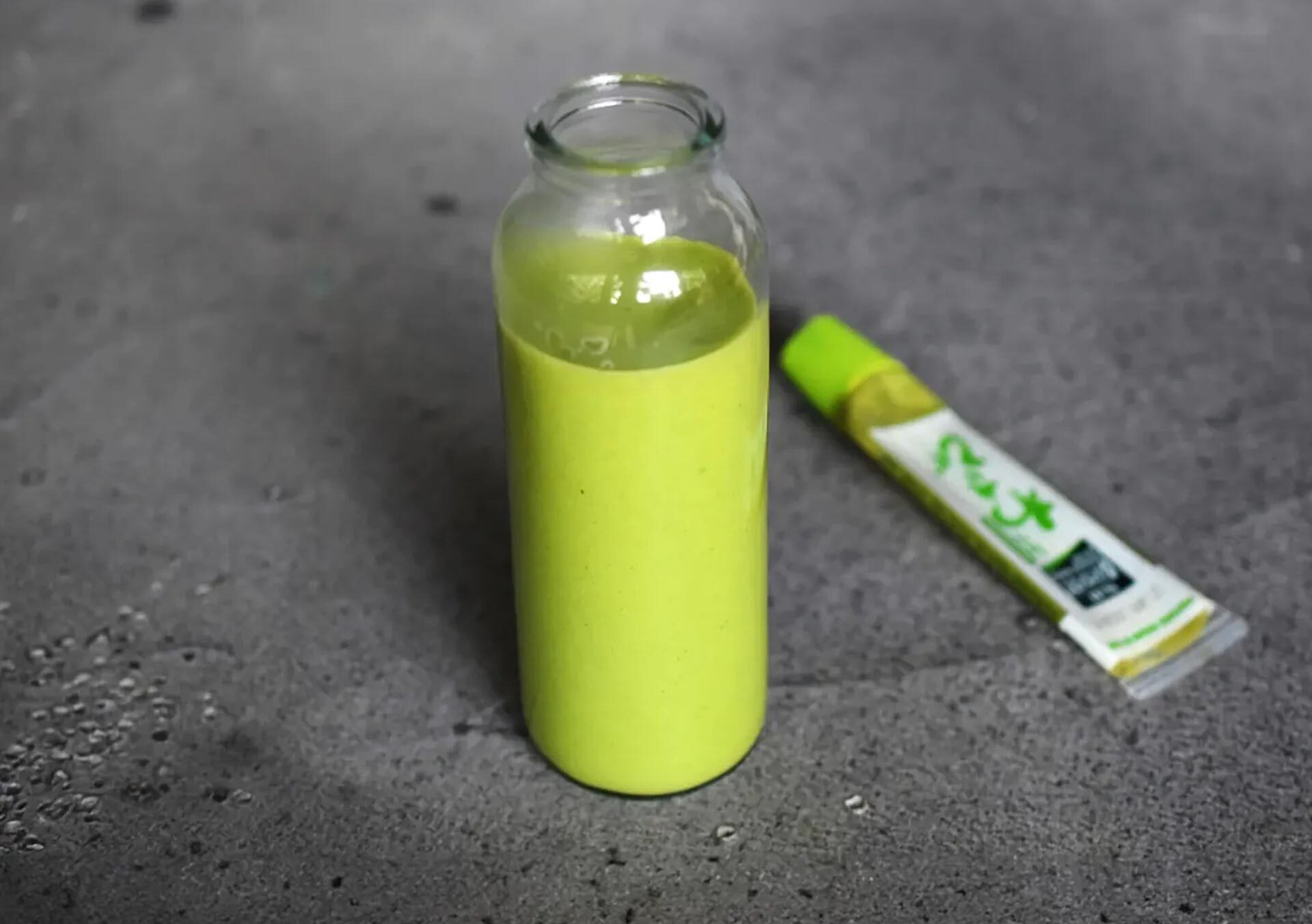 Glasflasche mit selbstgemachtem Wasabi-Dressing auf dunklem Untergrund