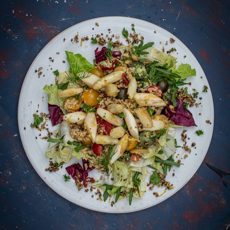 Bunter Salat mit Spargel, Quinoa, Tomaten und Kräutern auf Teller, verfeinert mit Verbena Grapefruitpfeffer der Gewürzmühle Rosenheim