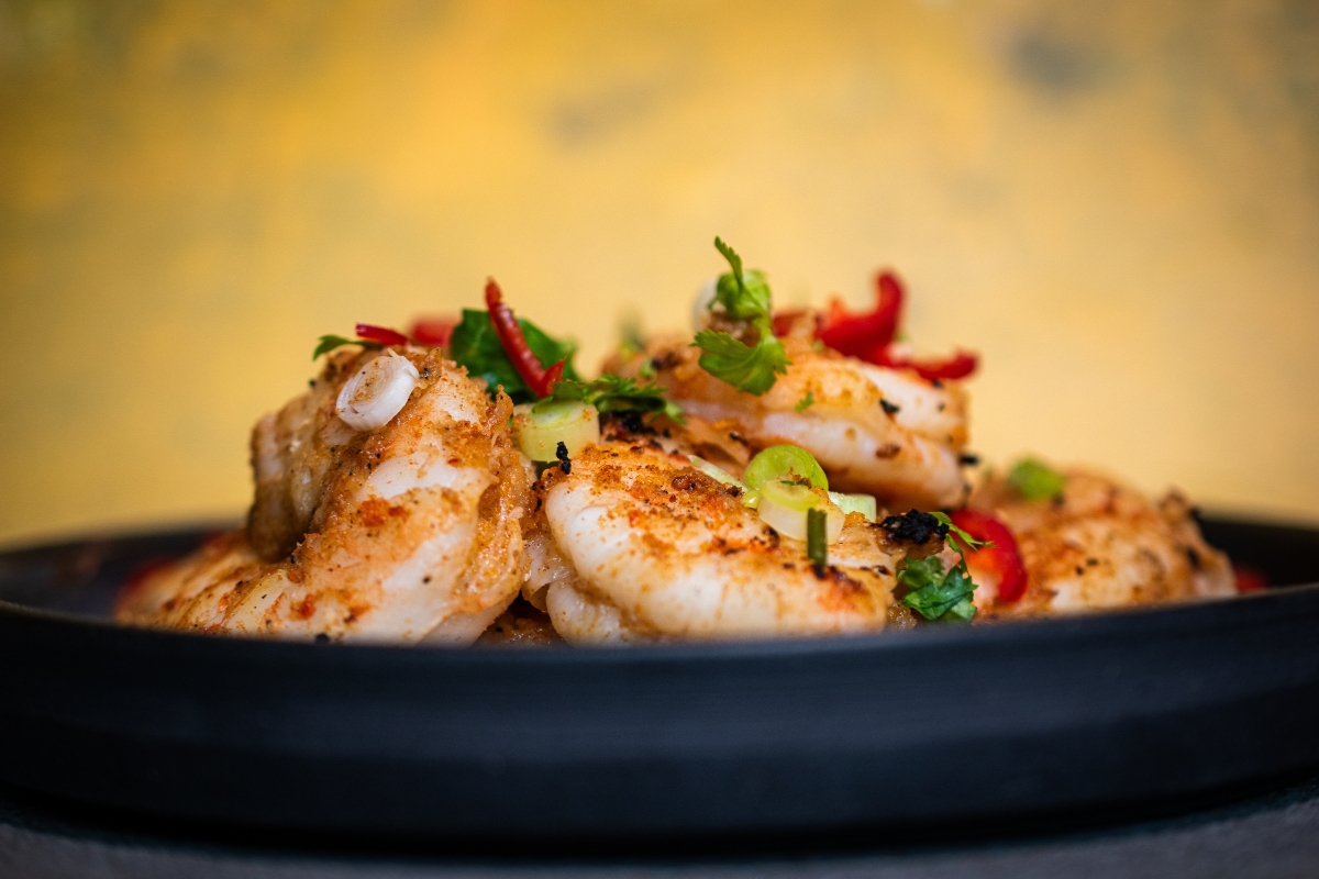 Ananas Teriyaki Garnelen Ananas Teriyaki Garnelen auf einem Teller serviert, und von der Seite Fotografiert vor gelben Hintergrund