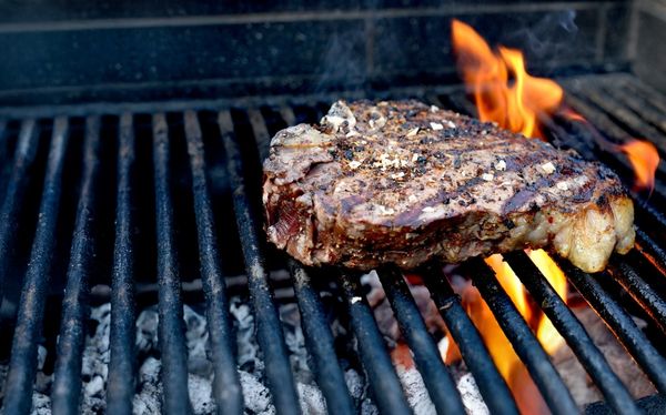 Grillen (2) - Header mobile Grillrost mit züngelnden Flammen und einem gewürzten Steak