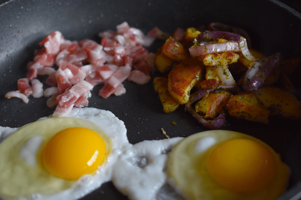 Spiegeleier, Speck und Bratkartoffeln in der Pfanne