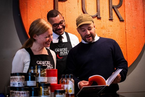 Simon mit zwei weiteren Mitarbeitern aus der Gewürzmühle, wie sie in dem "SPICED" Kochbuch lesen