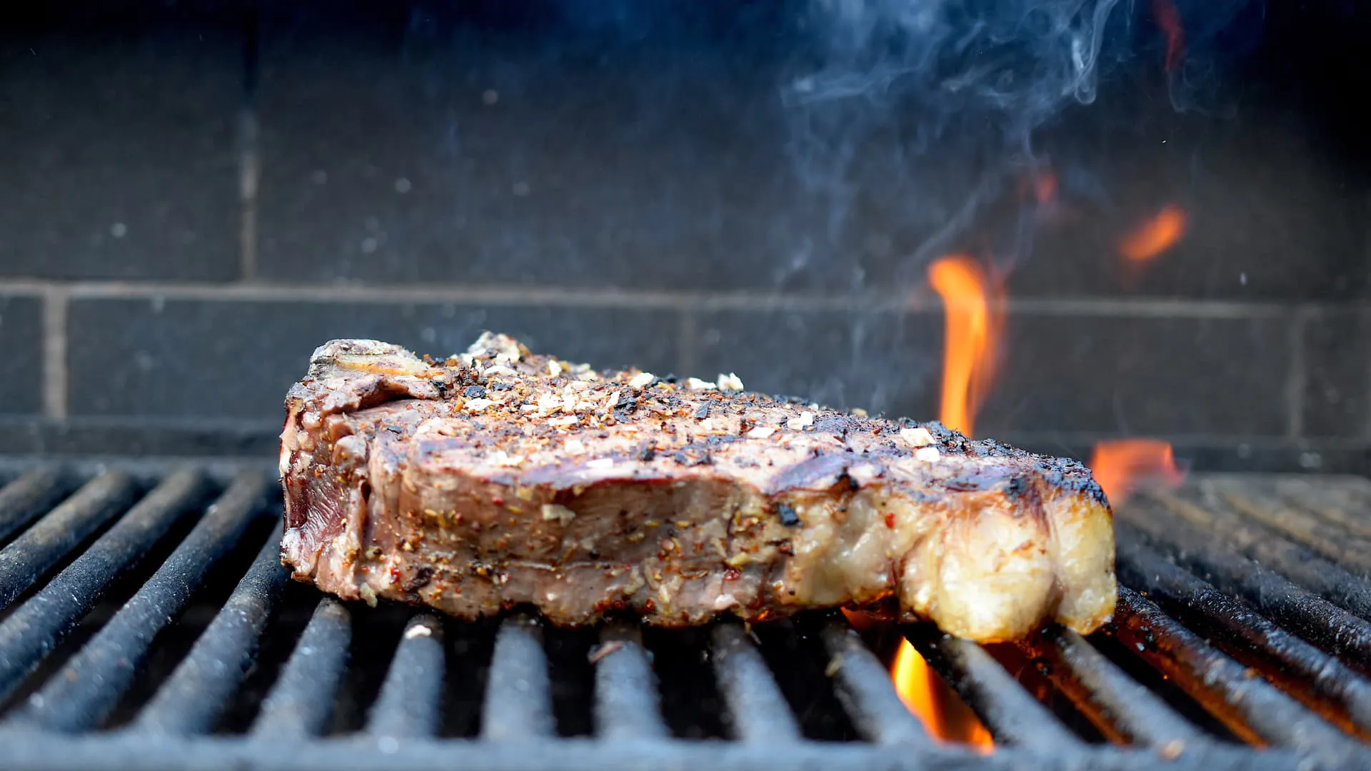 Steak auf Grill mit Rauch und Flammen