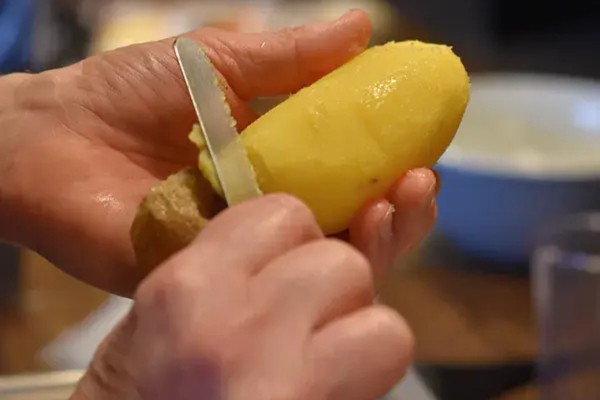 Schale wird von einer gekochten Kartoffel entfernt