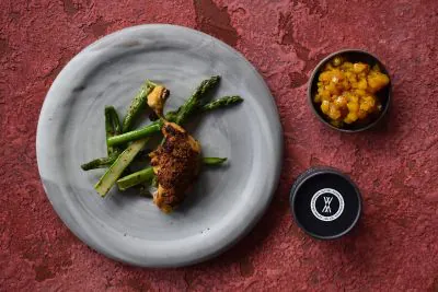 Baharathuhn mit Spargel auf einem Teller und einer Schale mit Chutney daneben